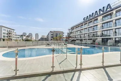 a large swimming pool in front of a building at Inviting Studio Overlooking the Pool, Just a Short Drive from Dubai Autodrome, Samana Golf Avenue, Dubai Studio City by Deluxe Holiday Homes in Dubai