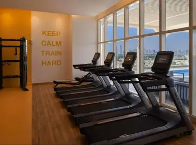 a row of treadmills in a fitness room at Vogue JVT Novotel near Springs Souk Mall, One Bedroom apartment with Balcony and Vibrant Community View, Access to all Amenities in Dubai