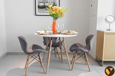 a dining room table with chairs and a vase with flowers at Vogue JVT Novotel near Springs Souk Mall, One Bedroom apartment with Balcony and Vibrant Community View, Access to all Amenities in Dubai