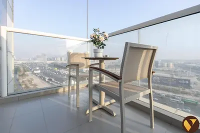 a table and two chairs on a balcony with a view at Vogue JVT Novotel near Springs Souk Mall, Studio Apartment with Balcony and City View, Access to all Amenities in Dubai