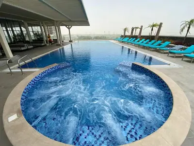 a large swimming pool with blue chairs in a building at Vogue JVT Novotel near Springs Souk Mall, Studio Apartment with Balcony and City View, Access to all Amenities in Dubai