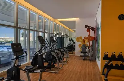 a gym with a row of treadmills and exercise bikes at Vogue JVT Novotel near Springs Souk Mall, Studio Apartment with Balcony and City View, Access to all Amenities in Dubai