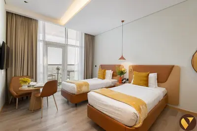 a hotel room with two beds and a table at Vogue JVT Novotel near Springs Souk Mall, Studio Apartment with Balcony and City View, Access to all Amenities in Dubai