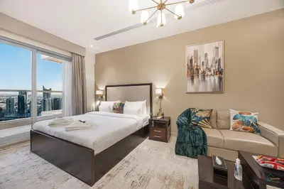 a bedroom with a bed and a couch and a window at Luxury Studio Retreat! Heart of Downtown Dubai! in Sabkhah