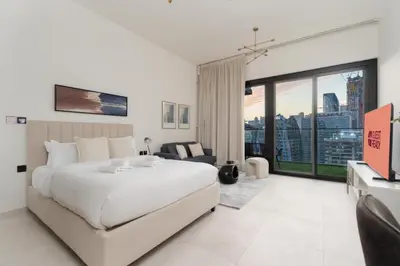 a bedroom with a large white bed and a large window at GuestReady - Studio l Partial Burj Khalifa View in Dubai