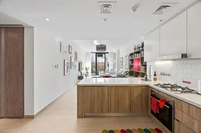 a large kitchen with white walls and wooden cabinets at Trendy Marina 2-Bedroom Apartment in Dubai