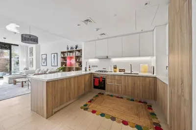 a kitchen with white cabinets and a rug on the floor at Trendy Marina 2-Bedroom Apartment in Dubai
