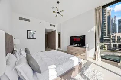 a white bedroom with a large bed and a tv at Trendy Marina 2-Bedroom Apartment in Dubai