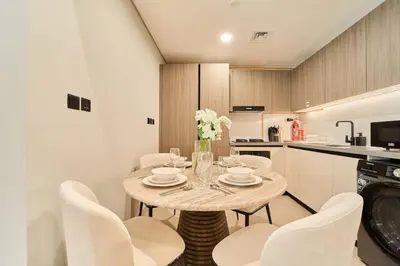 a kitchen and dining room with a table and chairs at Fresh and Modern 1BR Welcome to Asak 11 JVC in Dubai