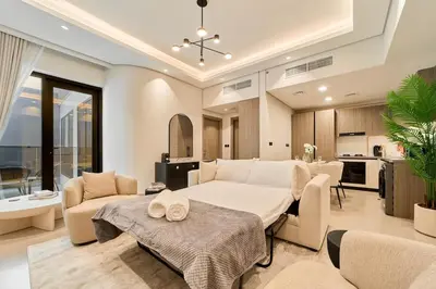 a large living room with a large bed and a kitchen at Fresh and Modern 1BR Welcome to Asak 11 JVC in Dubai