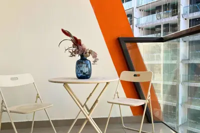 a table with two chairs and a vase with flowers on it at Coozy one bedroom in Al Jaddaf Dubai in Dubai