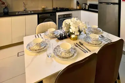 a table with plates and cups and a vase of flowers at Coozy one bedroom in Al Jaddaf Dubai in Dubai