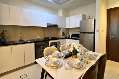 a kitchen with a table with chairs and a refrigerator at Coozy one bedroom in Al Jaddaf Dubai in Dubai