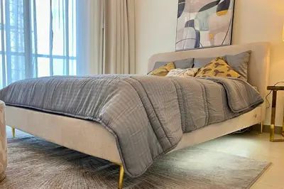 a bed with a gray blanket on it in a room at Coozy one bedroom in Al Jaddaf Dubai in Dubai
