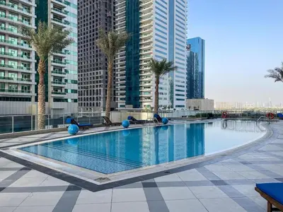 a large swimming pool with palm trees and tall buildings at The Torch Cozy 1BR Marina Near JBR & Metro in Dubai