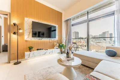 a living room with a couch and a large window at Community View 1BR, Just 15minutes to Miracle Garden - Oxford Boulevard, Jumeirah Village Circle by Deluxe Holiday Homes in Dubai