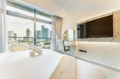 a hotel room with a large bed and a large window at Community View 1BR, Just 15minutes to Miracle Garden - Oxford Boulevard, Jumeirah Village Circle by Deluxe Holiday Homes in Dubai