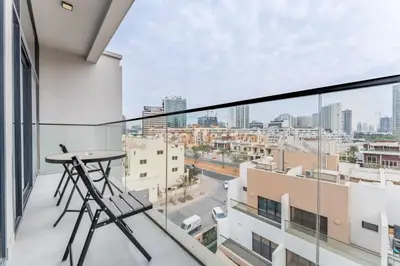 a balcony with a table and a view of a city at Community View 1BR, Just 15minutes to Miracle Garden - Oxford Boulevard, Jumeirah Village Circle by Deluxe Holiday Homes in Dubai