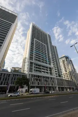 a tall white building on the side of a street at 1BR Facing Canal and City Views, Just a Short Walk to Bus Stop and Marine Transport, Reva Residences, Business Bay by Deluxe Holiday Homes in Dubai