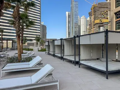 a rooftop patio with benches and palm trees in a city at Luxury 1Bed with Canal Views Near Burj Khalifa in Dubai