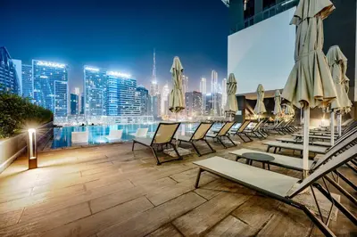 a rooftop patio with chairs and tables and a city skyline at StayShort - 1 Bedroom Sleeps 2 with City Views in Business Bay in Dubai