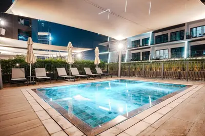 a swimming pool with chairs and a building at StayShort - 1 Bedroom Sleeps 2 with City Views in Business Bay in Dubai