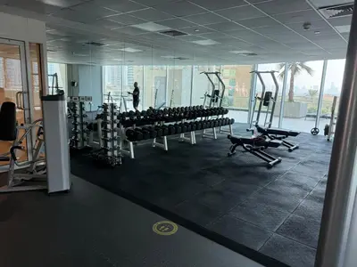 a gym with rows of exercise equipment and a man in the background at Spacious 1Bed with Golf Course and Marina View in Dubai