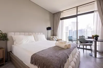 a bedroom with a large bed with a large window at Cozy studio with Burj Khalifa and canal view in Dubai