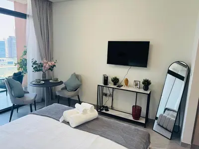a hotel room with a bed and a flat screen tv at Cozy studio with Burj Khalifa and canal view in Dubai