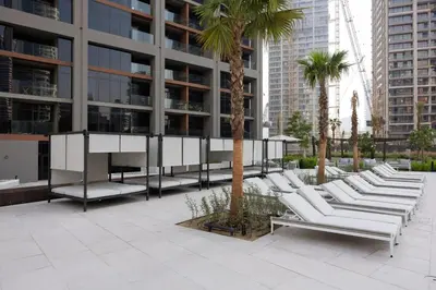 a row of white lounge chairs in front of a building at Cozy studio with Burj Khalifa and canal view in Dubai