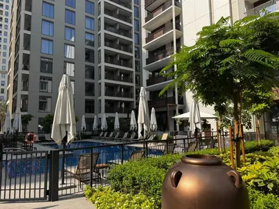 a large vase next to a pool with umbrellas at Elegant 1BR at Lotus Creek Beach Lagoon Living in Dubai