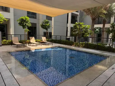 a swimming pool with chairs and a building at Elegant 1BR at Lotus Creek Beach Lagoon Living in Dubai