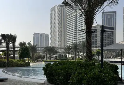a pool with palm trees and buildings in a city at Elegant 1BR at Lotus Creek Beach Lagoon Living in Dubai