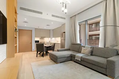 a living room with a couch and a table at Elegant 1BR at Lotus Creek Beach Lagoon Living in Dubai