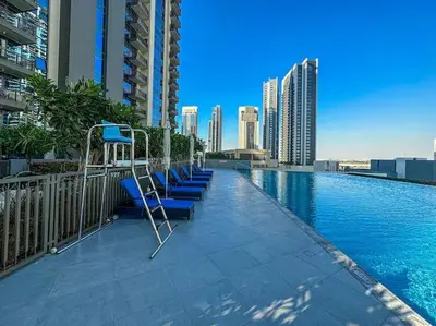 a row of blue chairs sitting on the side of a swimming pool at Spacious 1BR in Creek Harbour with Gym and Pool in Dubai