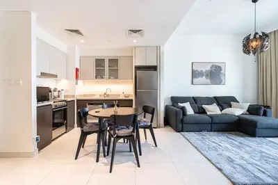 a living room with a blue couch and a table at Spacious 1BR in Creek Harbour with Gym and Pool in Dubai