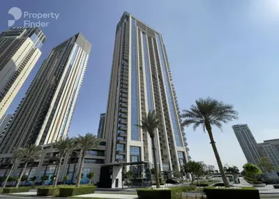 a tall building with palm trees in front of it at Spacious 1BR in Creek Harbour with Gym and Pool in Dubai