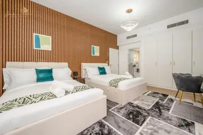 a bedroom with two beds and a chair at Deluxe Beach Residence 2Bhk, 8pax in Dubai