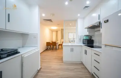 a kitchen with white cabinets and a dining room at Deluxe Beach Residence 2Bhk, 8pax in Dubai