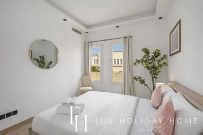 a white bedroom with a bed and a mirror at LUX The Serene Springs Villa in Dubai
