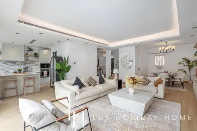 a living room with white furniture and a kitchen at LUX The Serene Springs Villa in Dubai