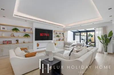 a living room with white furniture and a tv at LUX The Serene Springs Villa in Dubai