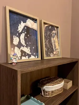 two framed pictures on a wooden shelf with a basket at Modern Japanese and Arabic Fusion City Stay that is 10 min from Dubai Mall in Dubai