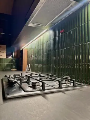 a gas stove in a kitchen with green walls at Modern Japanese and Arabic Fusion City Stay that is 10 min from Dubai Mall in Dubai