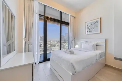 a bedroom with a white bed and a large window at Elegant 2BR Getaway in Azizi Riviera Near Downtown in Dubai