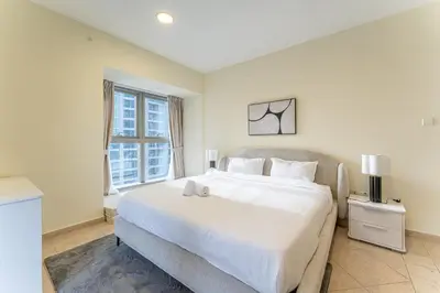 a bedroom with a large white bed and a window at HAVN - High Floor 2 Bedroom in Marina, near Tram in Dubai