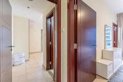 a hallway with a wooden door and a hallway with white cabinets at HAVN - High Floor 2 Bedroom in Marina, near Tram in Dubai