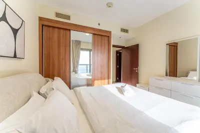 a bedroom with a large white bed and a mirror at HAVN - High Floor 2 Bedroom in Marina, near Tram in Dubai