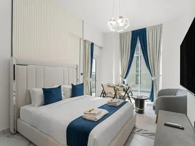 a bedroom with a large bed with blue pillows at Opalz Solace Cozy Luxe Studio 03 in Dubai