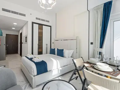 a bedroom with a large bed and a dining room at Opalz Solace Cozy Luxe Studio 03 in Dubai